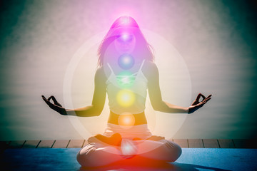 Young woman in yoga meditation with seven chakras and Yin Yang symbols.