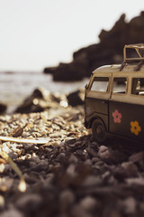 Vintage toy van on beach pebbles, sea and rocks in background