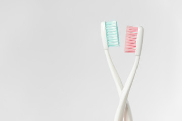 Close up of two plastic white toothbrushes with pink and blue bristle on white background. Free...