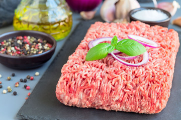 Minced meat from pork and beef. Ground meat with ingredients for cooking on dark slate board, horizontal