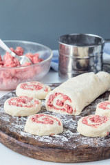 Making savoury cottage cheese pies with minced meat. Raw pies on wooden board, ingredients on background, vertical