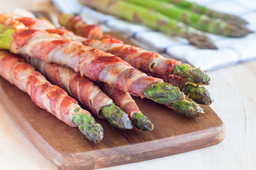 Healthy appetizer, green asparagus wrapped with bacon on wooden board, horizontal