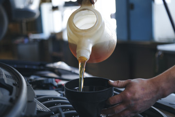 Pouring oil to car engine, close up