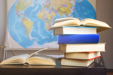 Composition of books and studies on table with world map hanging on wall