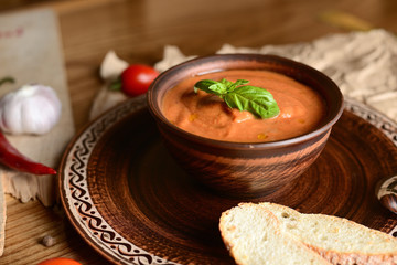 tomato cream soup with basil on a wooden table