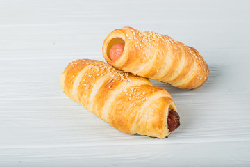 Sausages wrapped in puff pastry. Sausages in a dough on a wooden background