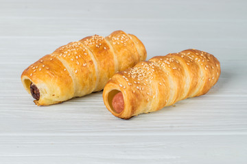 Sausages wrapped in puff pastry. Sausages in a dough on a wooden background