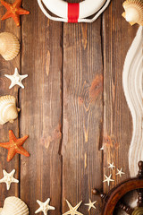 Yachting symbols - lifebuoy, ship's steering wheel, shells and beach sand on wooden background