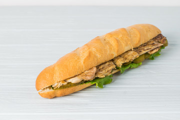 Fresh submarine sandwich with ham, cheese, tomatoes, cucumbers, lettuce and onions isolated on white background