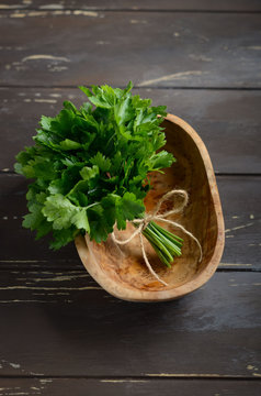 Fresh organic parsley bunch in a wooden bowl on the old rustic wooden table.