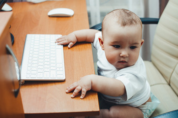 cute little baby girl typing on keyboard sitting at computer