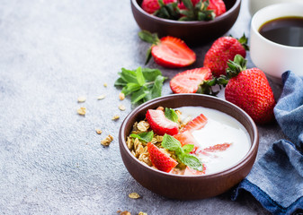 Breakfast with yogurt, granola of muesli and strawberries on gray concrete table background. Healthy Vegan Clean Diet Food Concept. Top view, copy space, flat lay