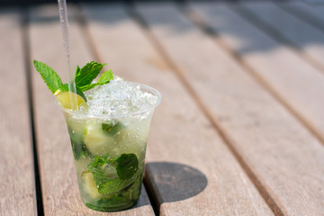 Mojito cocktail with ice, mint, lime and lemon on a bench
