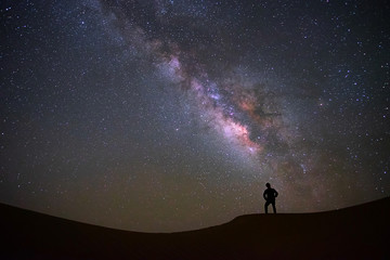 Milky way galaxy with a man standing and watching at Tar desert, Jaisalmer, India. Astro photography.