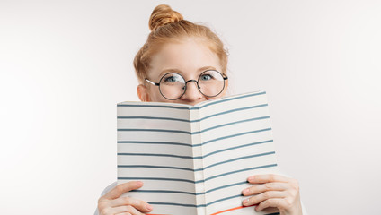 a cheerful cunning student pretending that she is reading a book. white background. school and...