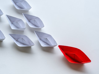 Leadership concept. Red paper ship lead among white. One leader ship leads other ships.