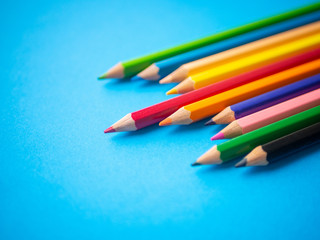 Closeup color pencils isolated on blue paper background. Education, Back to school Concept.