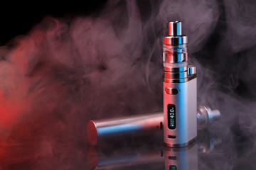 Electronic cigarette within vapor on black background. Toned light