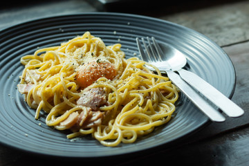 The spaghetti, fried cheese on a black plate on the table.