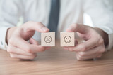 Close up smiley face icon and blurred sad on wood cube, Service rating, satisfaction concept.