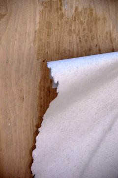 Feuchtes Poster l&ouml;st sich ab / Die Nahaufnahme einer Plakatwand aus Spanholz mit abgerissenen und nassen feuchten Papierfetzen von einem Poster.