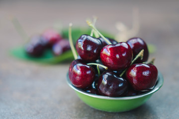 Fresh organic cherries in green bowl with selective focus point