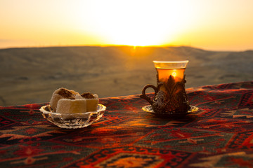 Eastern black tea in glass on a eastern carpet. Eastern tea concept. Armudu traditional cup. Sunset...