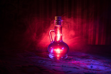 Antique and vintage glass bottles on dark foggy background with light. Poison or magic liquid...