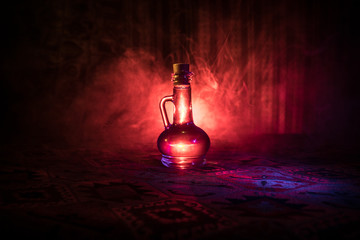 Antique and vintage glass bottles on dark foggy background with light. Poison or magic liquid...