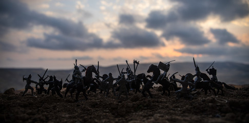 Medieval battle scene with cavalry and infantry. Silhouettes of figures as separate objects, fight between warriors on sunset foggy background. - obrazy, fototapety, plakaty