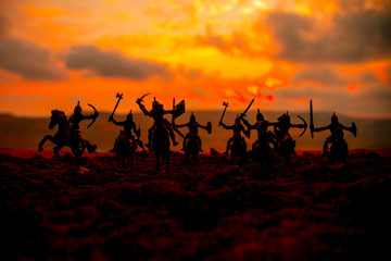 Medieval battle scene with cavalry and infantry. Silhouettes of figures as separate objects, fight between warriors on sunset foggy background.