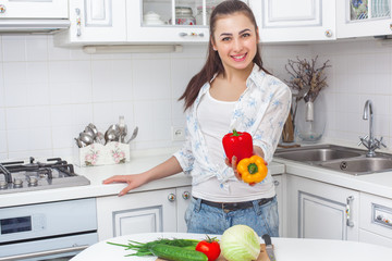 Young attractive woman cooking salad indoors at the kitchen