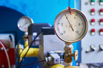 A gauge showing the gas pressure is installed on the pipeline. Industrial background.