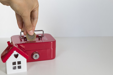 save money for real estate and mortgage investment.little house,red moneybox and coins on the white...