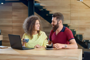 Happy smiling couple looking on each other drinking coffee in cafe.