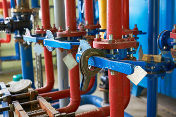 The blue valve on the hot water pipeline is painted red. Industrial background.