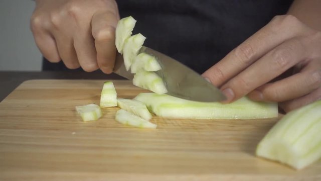 Slow motion - Close up of chief woman making salad healthy food and chopping cucumber on cutting board in the kitchen.