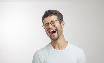 handsome unshaven young man laughing at a funny story facial expressions concept. isolated white...