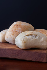 four white bread rolls on a wooden board