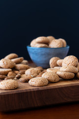 Amaretti biscuits in a bowl with almonds on a wooden board
