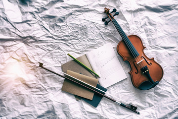 Fototapeta premium The abstract art design background of violin put beside the opened book and bow,blurry light around