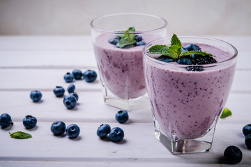 healthy smoothie or shake with fresh blueberries on a white wooden  background