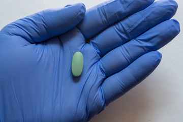 Close-up. Medical glove with Green oval tablets