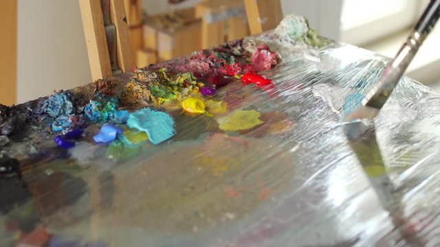 artist stirs paint brush before drawing painting