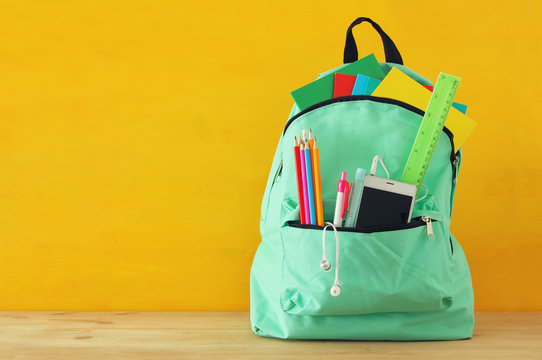 School Bag With Stationery And Notebooks In Front Of Wooden Yellow Background. Back To School Concept.