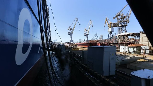 Panoramic view of the ship is blue standing in the port. The merchant ship is moored.