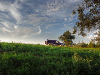 Fototapeta premium Off-road car on a country road in the field