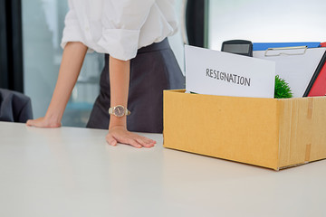  Business woman packing her belongings in cardboard box on desk leaving his office with his personal effects.