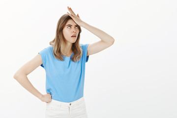 Girl being annoyed with dumb questioned. Portrait of displeased fed up funny girlfriend in blue t-shirt, punching forehead with palm and rolling eyelids, having no idea how person can be so stupid