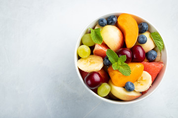 Bowl of healthy fresh fruit salad on a white background. Top view with copy space. Flat lay
